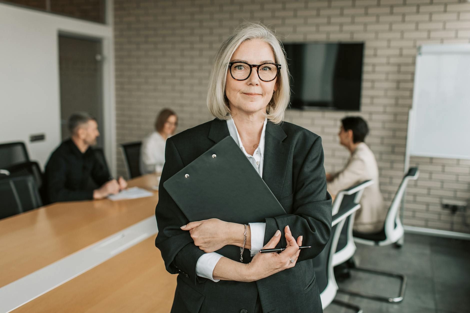 elderly woman in black blazer holing a clipboard